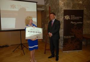 Prezes Dariusz Daniluk wręcza 100-miliardową złotówkę przedstawicielce PUP w Kielcach